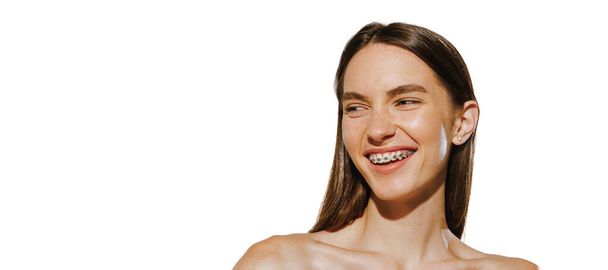 Muotokuva iloinen nuori tyttö hammasraudat. hymyilevä, poseeraa eristettynä valkoiselle taustalle. Hammashoito. Lentäjäkuva. Käsitys kauneus, luonnollinen iho, kosmetiikka, plastiikkakirurgia. Kopioi tilaa mainokselle - Valokuva, kuva