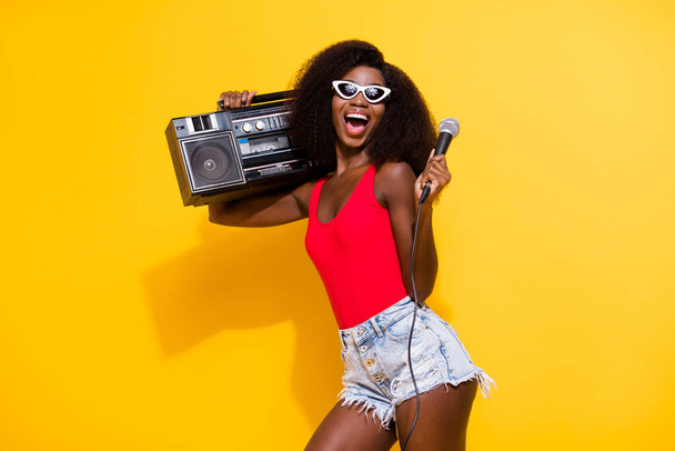 Portrait of attractive trendy cheerful ecstatic girl carrying boombox singing having fun isolated over bright yellow color background. - Fotografie, Obrázek