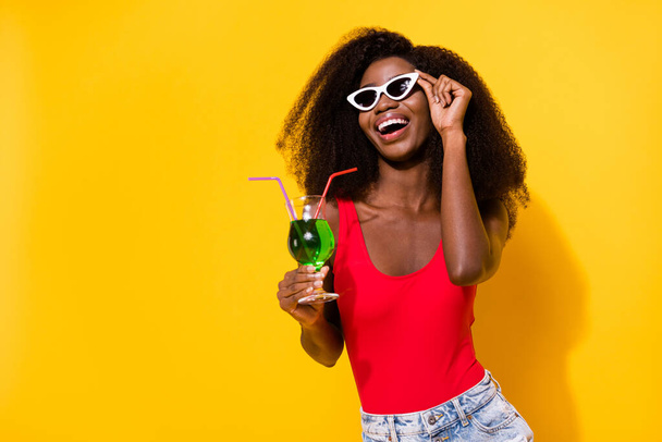 Photo of optimistic nice brunette lady hold drink look empty space wear spectacles top shorts isolated on yellow color background. - Valokuva, kuva
