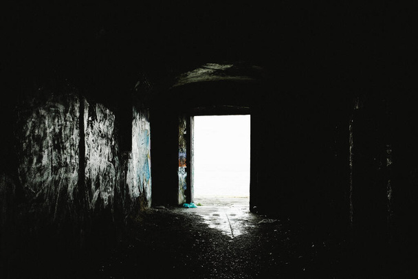 The daylight through the door behind a dark corridor - Foto, Imagen