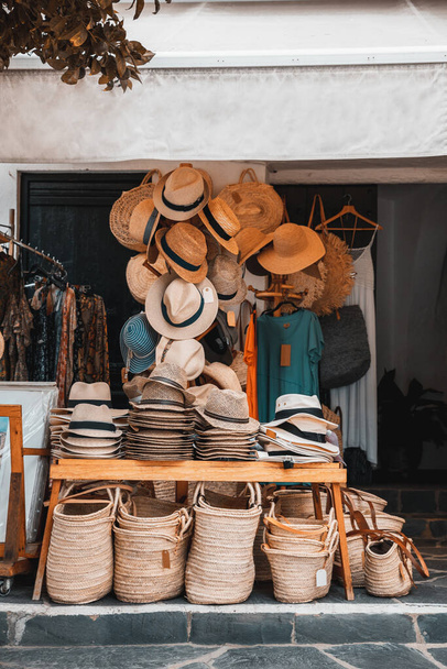 Παραδοσιακό κατάστημα με καπέλα και ψάθινες τσάντες, καλάθια και ρούχα στο δρόμο. Χειροποίητα αναμνηστικά προϊόντα για τους τουρίστες - Φωτογραφία, εικόνα
