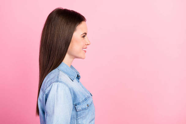 Side profile photo portrait of girl smiling in casual jeans shirt looking copyspace isolated on pastel pink color background. - Foto, imagen