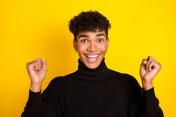 Photo of hooray brunet guy hands fists wear black sweater isolated on vibrant yellow color background. - 写真・画像