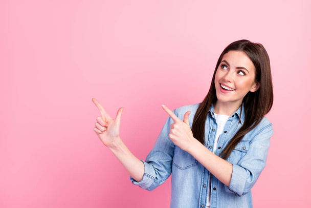 Photo portrait of female student showing finger looking empty space advising isolated on pastel pink color background. - Фото, изображение
