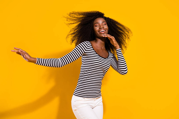 Photo portrait of curly woman dancing dreamy with flying hair isolated vivid yellow color background. - Foto, immagini