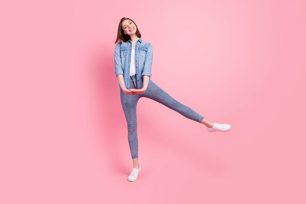 Full length body size photo girl smiling wearing jeans clothes playful isolated pastel pink color background. - Foto, immagini