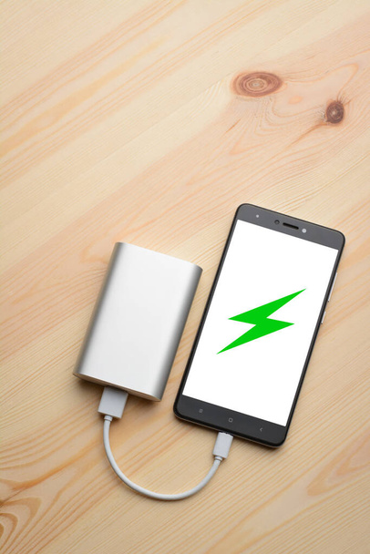 Mobile phone charging with power bank on wooden background - Photo, Image