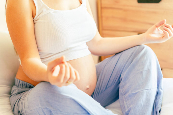 Medytacja jogi w ciąży. Zdrowa joga domowy sport. Piękna kobieta w ciąży medytująca podczas siedzenia w pozycji lotosu. Pojęcie macierzyństwa, ciąży, porodu - Zdjęcie, obraz