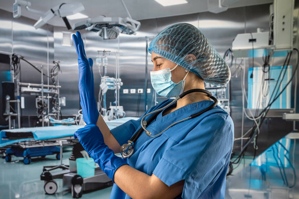 Női nővér visel kék egyenruhát maszkkal fel gumi latex kék kesztyű bonyolult műtéti beavatkozás - Fotó, kép