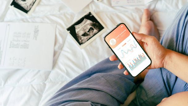 Pregnancy app. Mobile pregnancy online maternity application. Pregnant mother using phone. Pregnancy, medicine, pharmaceutics, health care and people concept - 写真・画像