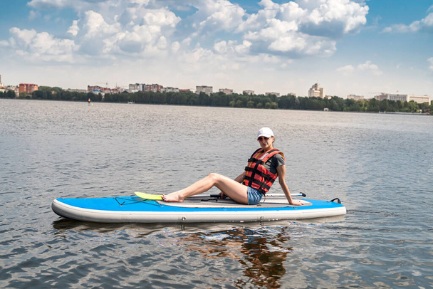  young woman wear life vest paddle boarding on a lovely lake at summer hot day, active lifestyle sport and relax - Photo, Image