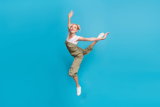 Full length photo of impressed young lady jump wear t-shirt grey overall footwear isolated on blue background. - Foto, Bild
