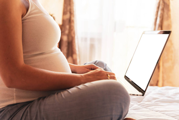 妊娠中のデジタル画面のモックアップ。ノートパソコンの画面を持っている妊婦。モバイル妊娠オンライン妊産婦アプリケーションのモックアップ。妊娠・産前・出産への期待 - 写真・画像