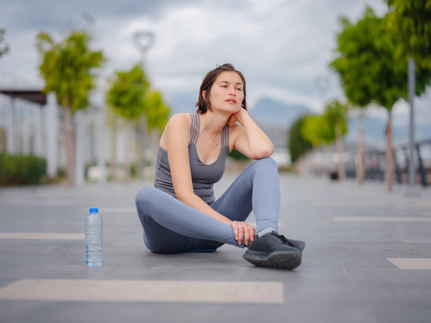 outdoor sports, workout and wellness concept. asian young strong, confident woman in sportive clothes Relaxing After Fitness Workout In Park. Female runner taking break from running sport. - Photo, Image