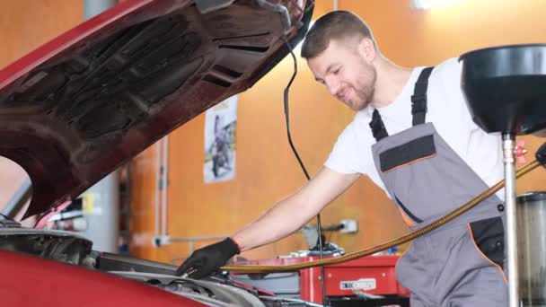 A mechanic man makes an oil change in a car. The concept of automotive automotive service. The work of a car mechanic - Footage, Video