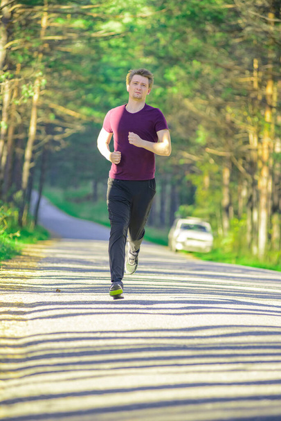 Running man jogging in city park at beautiful summer day. Sport fitness model caucasian ethnicity training outdoor. - Zdjęcie, obraz