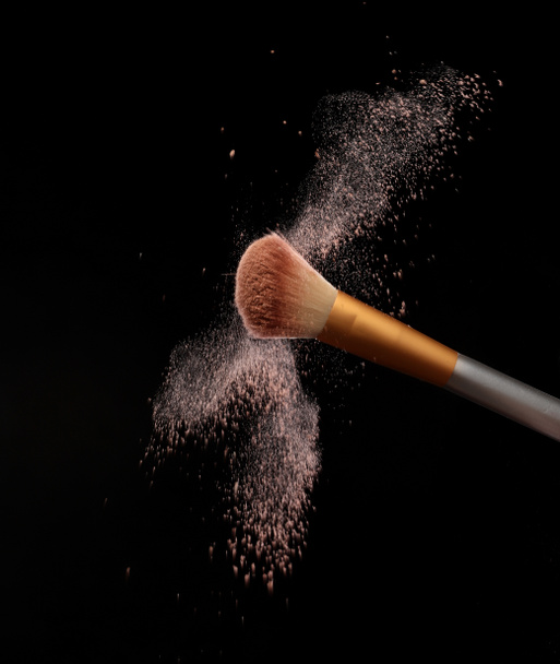 Βούρτσα μακιγιάζ με splash καλλυντική σκόνη, πάνω από μαύρο φόντο. Splash εικόνα - Φωτογραφία, εικόνα