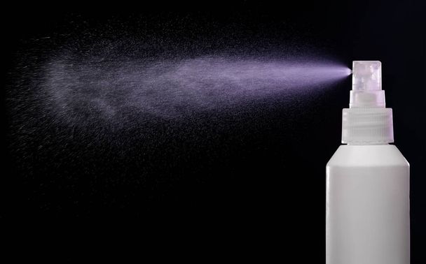 Spraying produkt ve spreji láhev přes černé pozadí - Fotografie, Obrázek