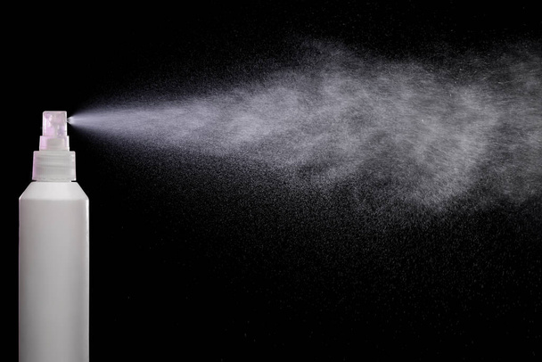 Spraying product in spray bottle over black background - Photo, Image