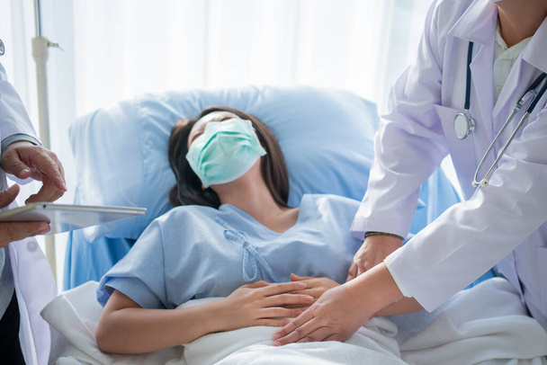 Μια ομάδα γιατρών προσπαθεί να βοηθήσει μια υπομονετική γυναίκα να ξαπλώσει στο κρεβάτι του νοσοκομείου και να υποφέρει από στομαχόπονο. Κοιλιακό πόνο που προέρχεται από έμμηνο ρύση, διάρροια, ή δυσπεψία. Έννοια ασθένειας και υγειονομικής περίθαλψης - Φωτογραφία, εικόνα