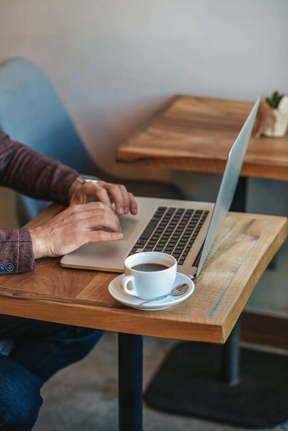 Inspiration. clavier de l'ordinateur portable mains sur la table avec café dans le café pendant la journée, sans visage - Photo, image