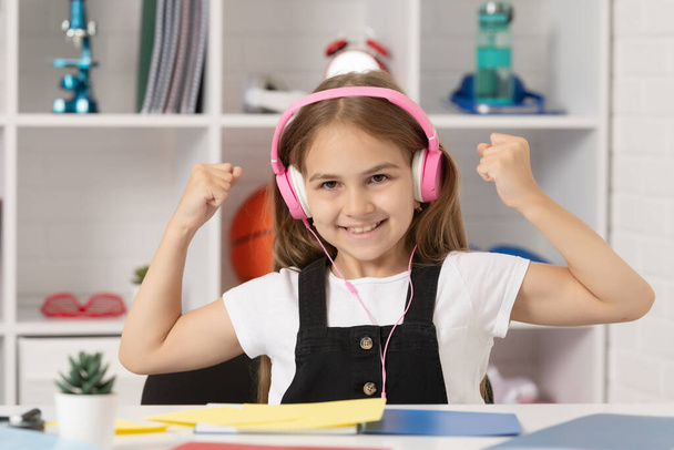 udany dzieciak słuchać muzyki w słuchawkach w klasie szkolnej. - Zdjęcie, obraz