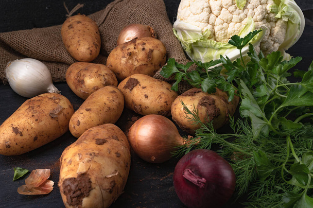 The potato, cabbage, onions and greens on a wooden table - Foto, Bild