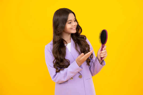 Κοριτσάκι με βούρτσα που χτενίζει τα μαλλιά. Κορίτσι που φροντίζει τα μαλλιά και το χτένισμα. Ευτυχισμένο πρόσωπο, θετικά και χαμογελαστά συναισθήματα της έφηβης κοπέλας - Φωτογραφία, εικόνα