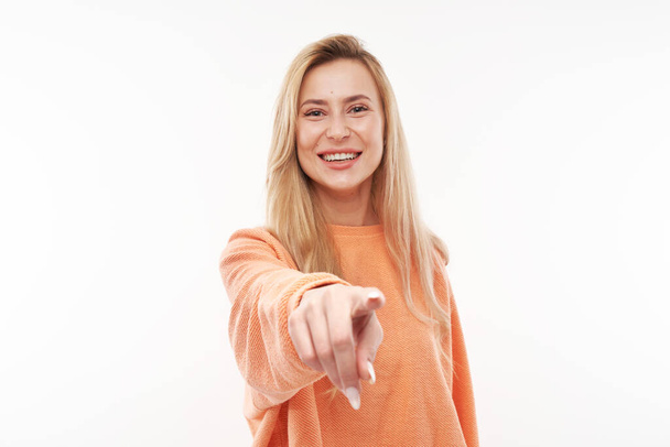 Portrait of friendly blonde girl chooses you, points finger at the camera isolated on white background - Foto, Imagen