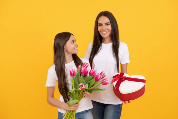 Женский день. счастливая мать и дочь с цветами тюльпана и подарок коробки. - Фото, изображение