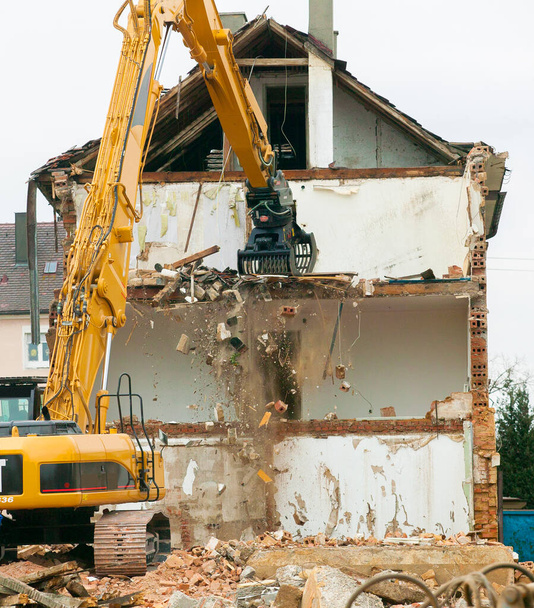 nagy teherbírású kotrógép lerombol egy régi lakóépületet. - Fotó, kép