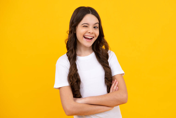Teenager child girl close one eye, winks and smiling. Human facial emotions concept. Funny winking face gesture. Happy teenager, positive and smiling emotions of teen girl - Photo, Image