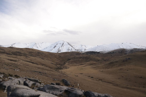 A shot of snowy mountains and dry hills in Castle Hill, Canterbury New Zealand - Foto, Imagen