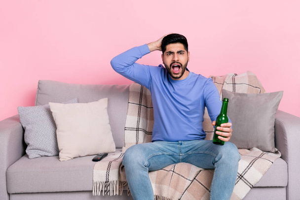 Photo of impressed unsatisfied person sitting couch hand touch head hold beer isolated on pink color background. - Фото, зображення