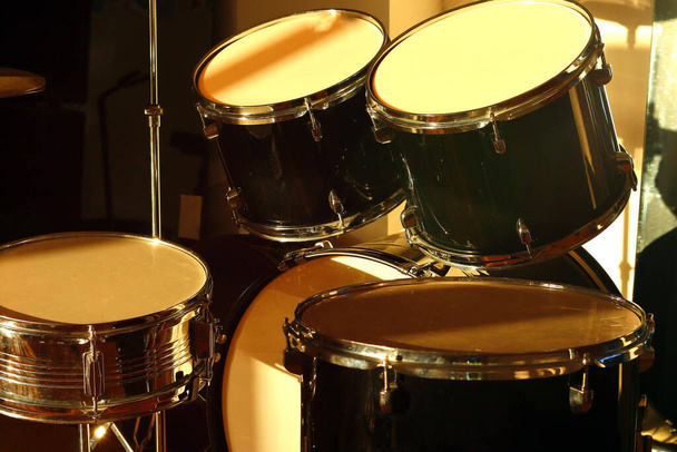 Conjunto de tambores iluminado por los rayos del sol poniente en un estudio de música. Primer plano.. - Foto, imagen