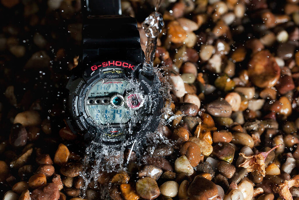 G shock digital watch surrounded by pebbles and being splashed with water - 写真・画像