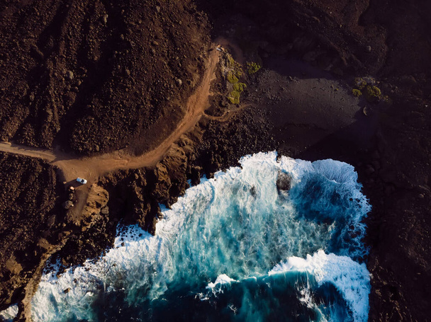 Вид с воздуха на пляж с лавой и океанскими волнами с тонами заката на острове Лансароте - Фото, изображение
