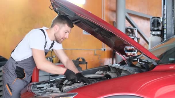 A handsome professional car service mechanic repairs a car engine. Car service. Diagnosis of a new car - Footage, Video