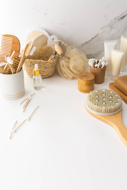 Cepillos de dientes de madera con cerdas naturales en un vaso de cerámica, productos para el cuidado de la cara y la piel, accesorios de baño, spa y concepto de belleza - Foto, imagen