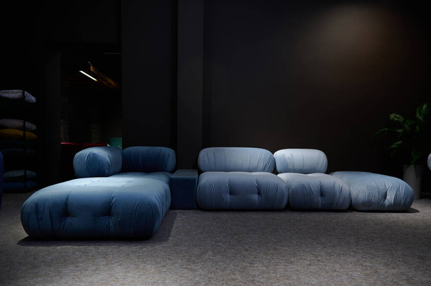 Стильный современный большой синий диван-кровать из сатина выставлен на продажу в мебельном магазине - Фото, изображение