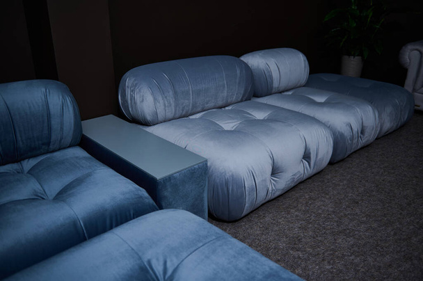 Частичный вид стильного синего атласного дивана, выставленного на продажу в мебельном магазине. Концепция дизайна интерьера - Фото, изображение