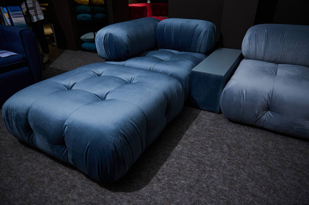 Обрезанный вид на стильный современный большой синий атласный диван-кровать, выставленный на продажу в мебельном магазине. Дизайн интерьера, декор, концепция улучшения дома - Фото, изображение