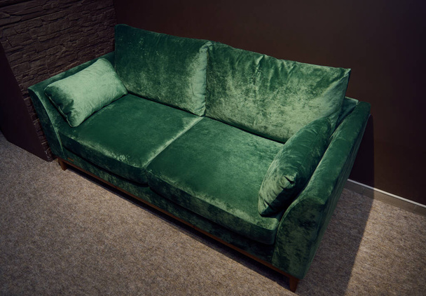Комфортний м'який велюровий зелений диван, що відображається на продаж в шоу-румі меблевого магазину. Виставка м'яких меблів
. - Фото, зображення
