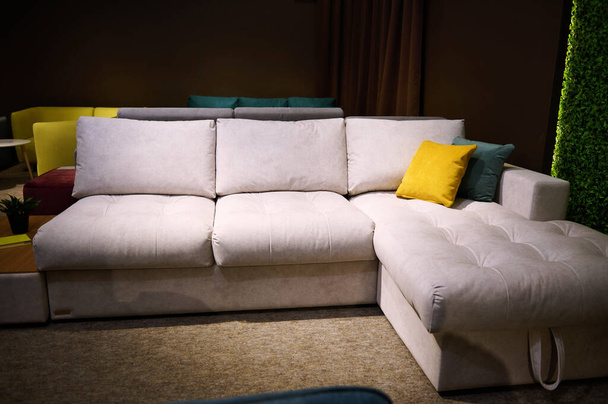 Krásná pohodlná béžová pohovka s jasnými polštáři vystavenými na prodej v ateliéru domácího designu a obchodě s nábytkem - Fotografie, Obrázek