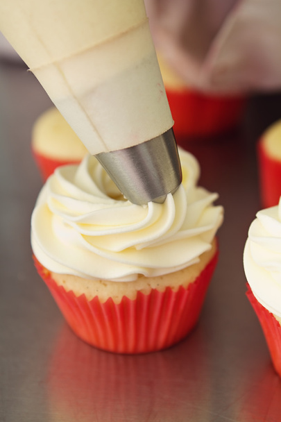 Frosting being applied to a vanilla cupcake - Fotografie, Obrázek