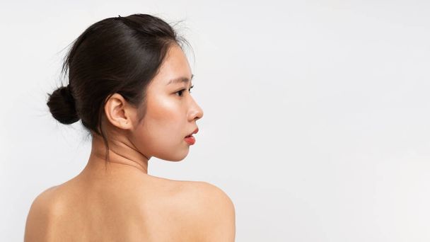Meztelen koreai hölgy pózol fehér stúdió háttérben, visszapillantás félmeztelen ázsiai nő nézi fénymásolás hely, panoráma. A női érzékiség fogalma - Fotó, kép