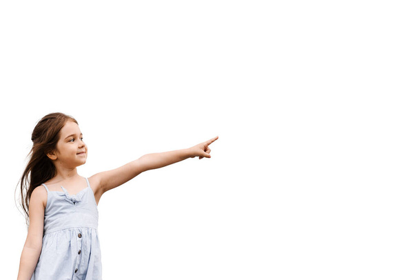 Urocza dziewczynka wskazująca palcem na białym tle z pustym miejscem na reklamę. Kreatywny pomysł na sprzedaż rabatów dla dzieci - Zdjęcie, obraz