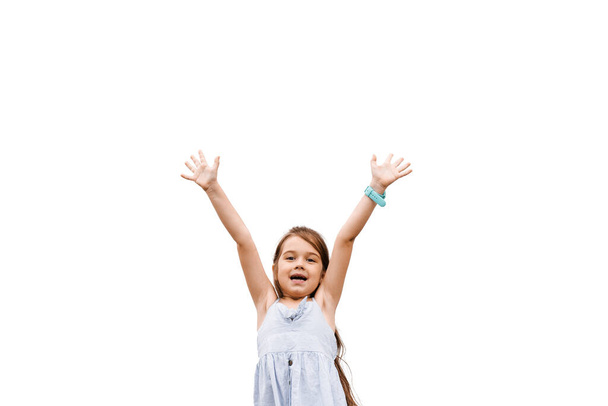 Positive happy child girl raise hands up, smiling and laughing on white background with empty place for adrert. Concept of win in online game - Foto, afbeelding