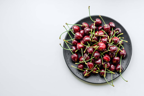 Fresh red cherries fruit on a plate on a white background. Close up - Fotografie, Obrázek