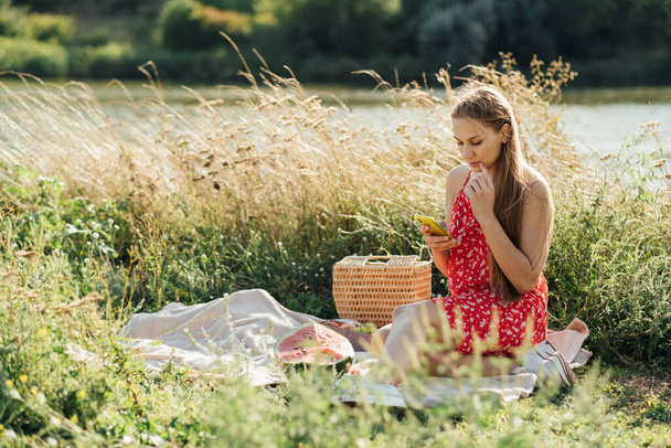 Sociale media internet verslaving, phubbing. jonge vrouw het lezen van sociale media op hun smartphones tijdens het hebben van dating picknick outdoor zomerdag - Foto, afbeelding